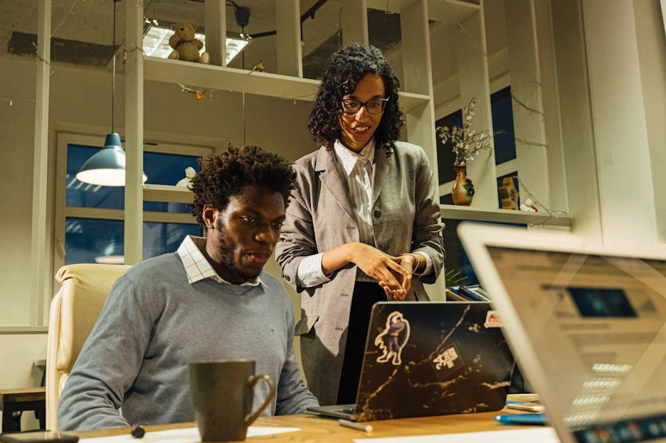 Un giovane team lead sorridente che lavora al suo laptop in un ambiente moderno